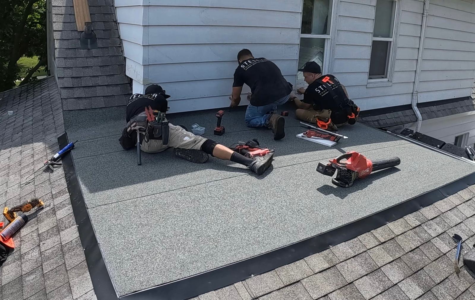 Stellar Roofing Company crew finishing a flat roof section where it meets the siding