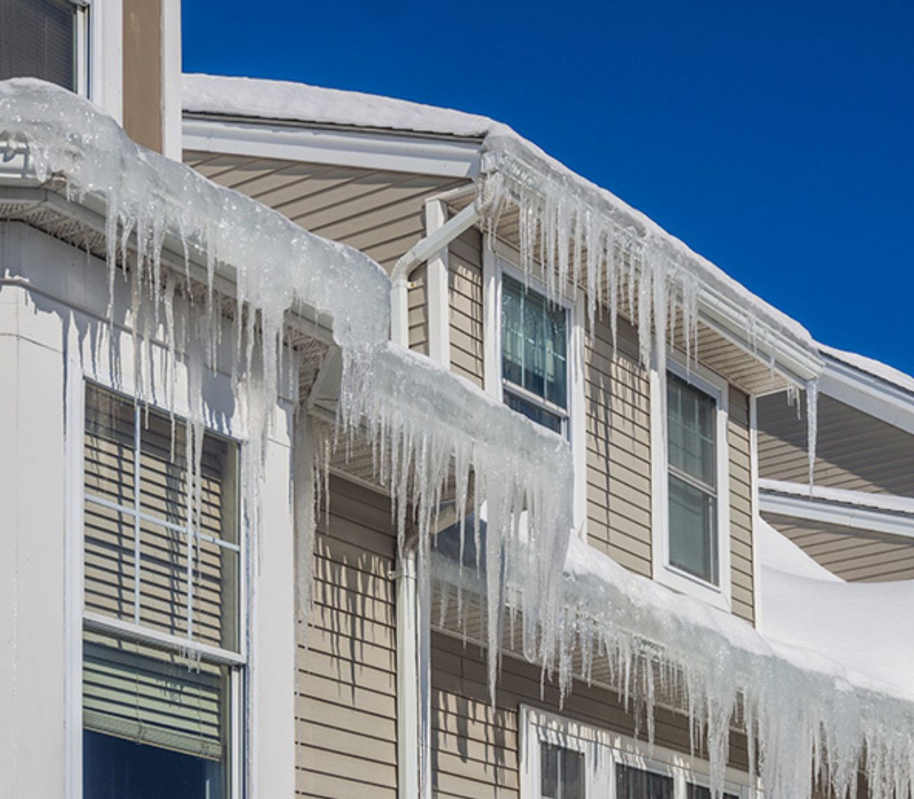 Ice dams and icicles hanging from snow-covered roof eaves and gutters