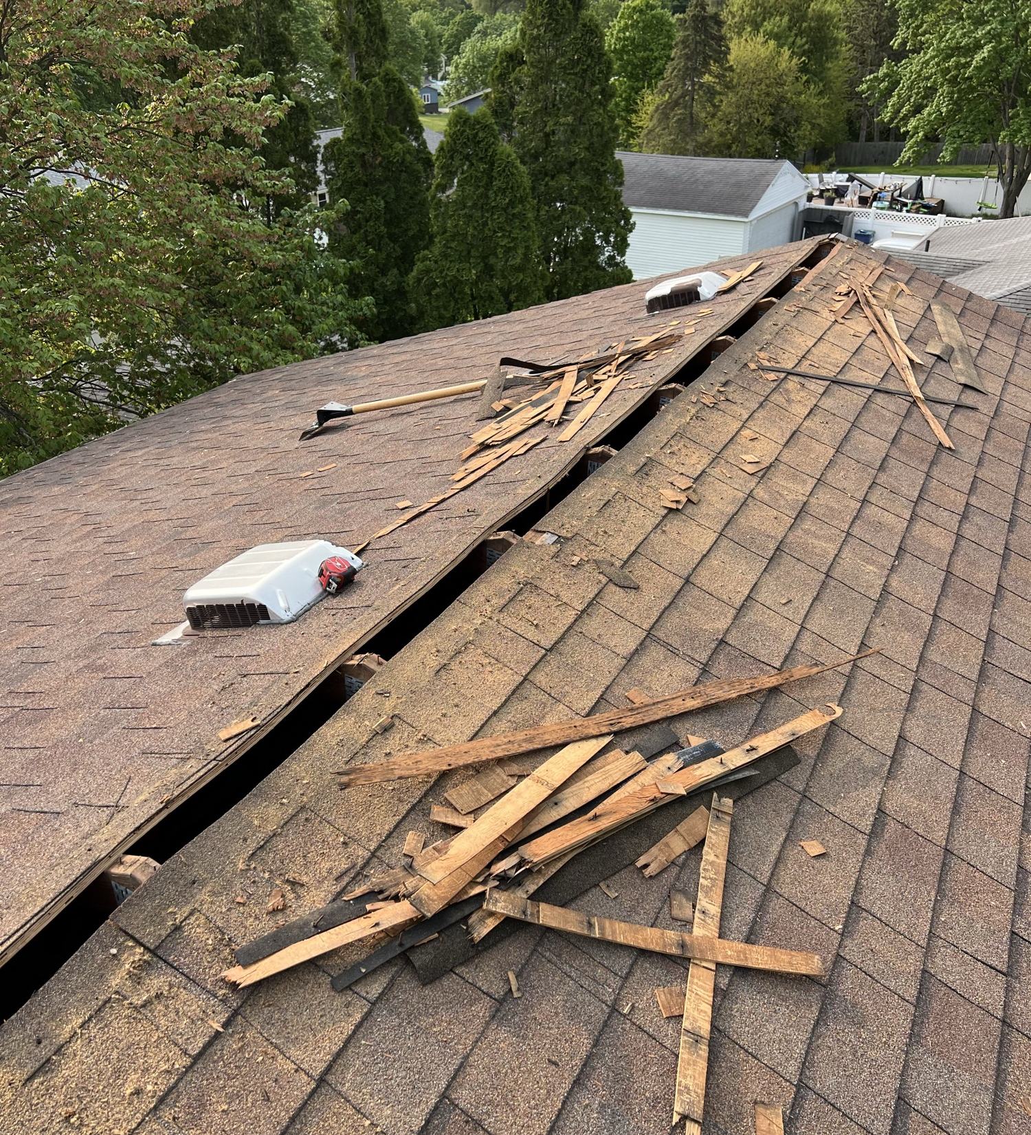 Shingle roof with the ridge cut open and old decking strips removed beside box vents